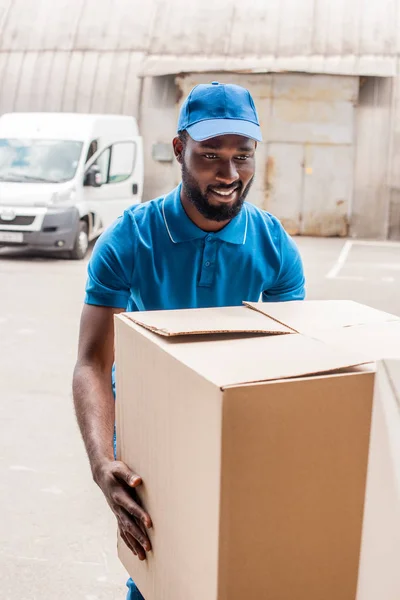 Africano americano entregador homem carregando grande caixa — Fotografia de Stock
