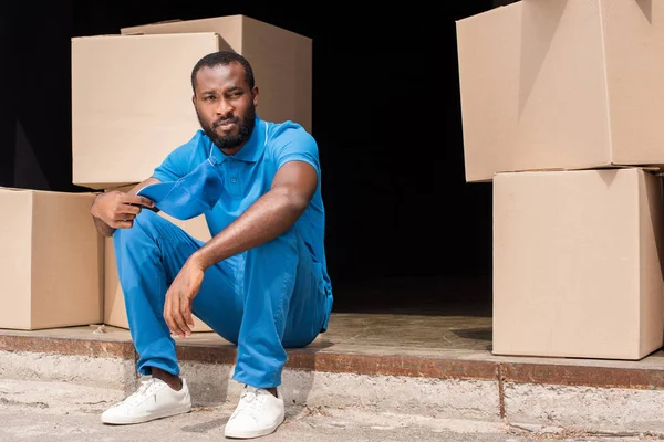 Афроамериканський чоловік доставки відпочиває біля коробки — стокове фото