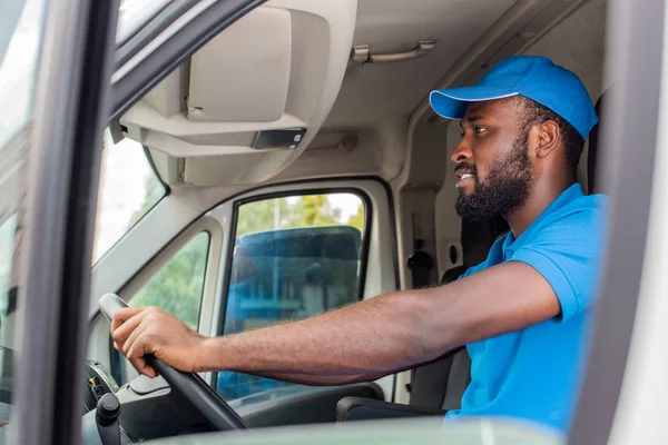Side view of african american delivery man driving van — Stock Photo
