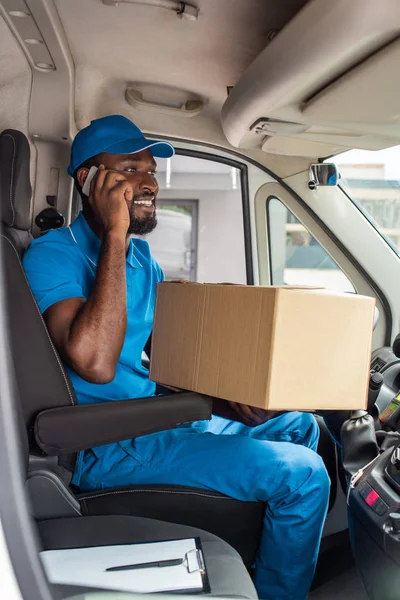 African american delivery man talking by smartphone in van — Stock Photo