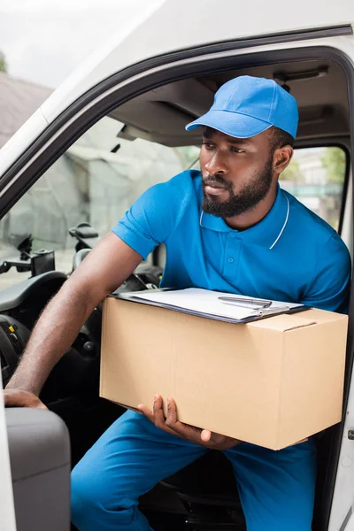 Afrikanisch-amerikanischer Zusteller steigt mit Kiste aus Auto aus — Stockfoto