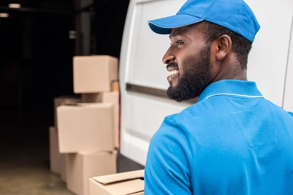 Seitenansicht eines lächelnden afrikanisch-amerikanischen Lieferanten, der wegschaut — Stockfoto