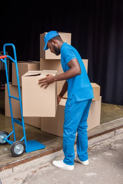 Correio americano africano colocando caixas no carrinho — Fotografia de Stock