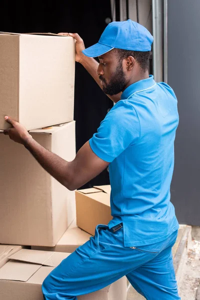 Africano americano repartidor poniendo cajas uno en el otro - foto de stock
