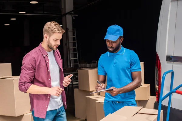 Mensajero afroamericano sosteniendo pluma y portapapeles - foto de stock