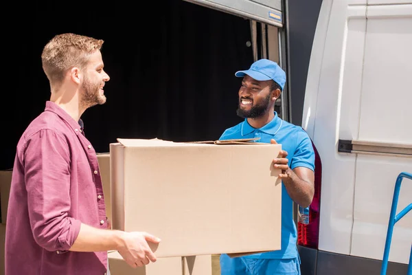 Coursier afro-américain et client caucasien tenant boîte de livraison — Photo de stock