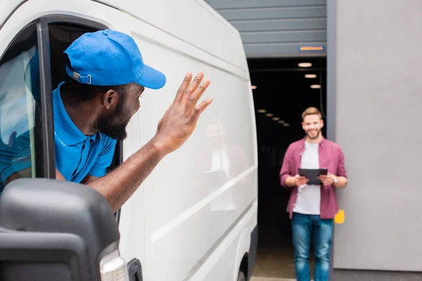 African american courier waving hand to client — Stock Photo