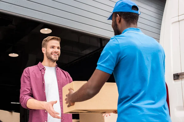 Courrier afro-américain donnant boîte de livraison au client — Photo de stock