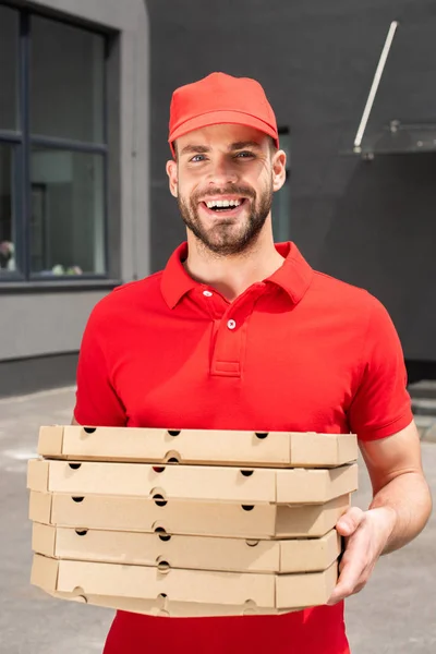 Corriere caucasico sorridente che tiene scatole con pizza — Foto stock