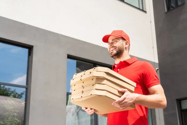 Vista a basso angolo del fattorino caucasico che trasporta scatole di pizza — Foto stock