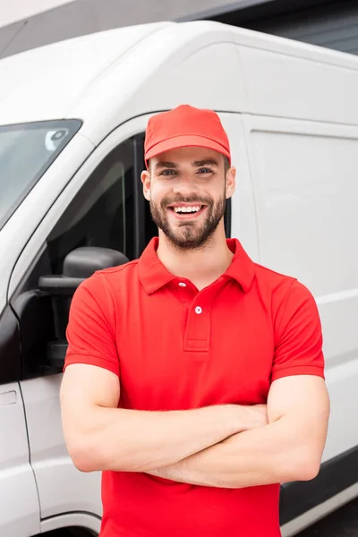 Uomo consegna caucasico sorridente in piedi con le braccia incrociate e guardando la fotocamera vicino al furgone — Foto stock