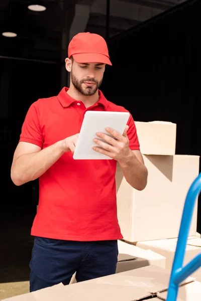 Retrato del repartidor hombre en uniforme rojo usando tableta digital - foto de stock