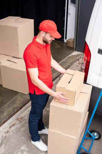 High angle view of young delivery man discharging cardboard boxes from van — Stock Photo