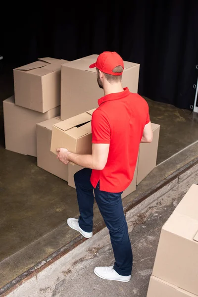 Haute vue ange de jeune livreur en uniforme rouge déchargeant la cargaison — Photo de stock