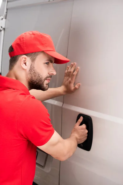 Vue latérale du jeune livreur ouvrant la porte du fourgon — Photo de stock