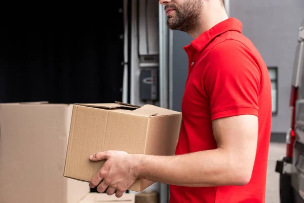 Partial view of delivery man discharging cardboard boxes from van — Stock Photo