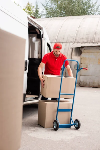 Молодий чоловік з доставки вивантажує картонні коробки з фургона — стокове фото