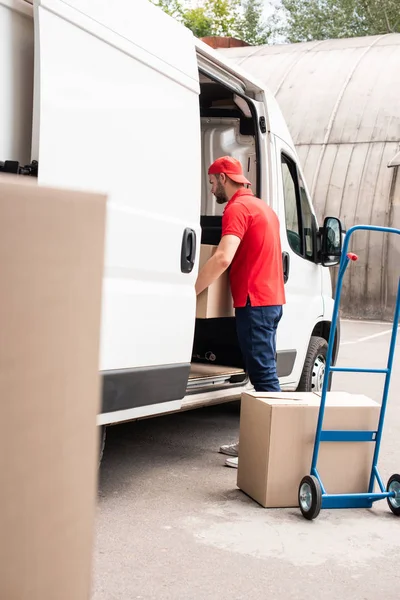 Молодий чоловік з доставки вивантажує картонні коробки з фургона — стокове фото