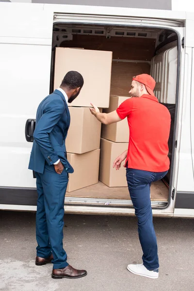 Caucasian delivery man showing cargo to african american client — Stock Photo