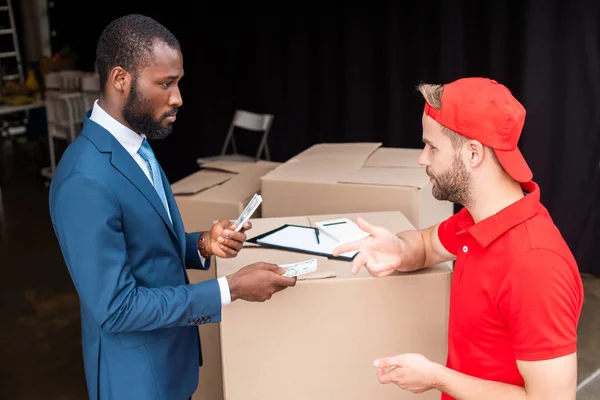 Side view of african american client paying for delivery with cash — Stock Photo
