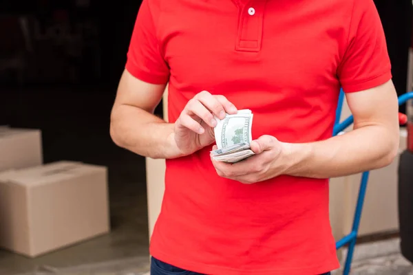 Visão parcial do homem de entrega contando dinheiro nas mãos — Fotografia de Stock