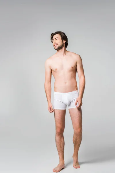 Cher homme en sous-vêtements blancs regardant loin sur fond gris — Photo de stock