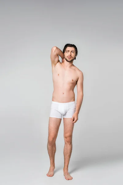 Uomo pensieroso in biancheria intima bianca in posa su sfondo grigio — Foto stock