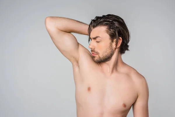 Портрет красивого мужчины без рубашки с поднятой рукой, изолированного на сером — стоковое фото