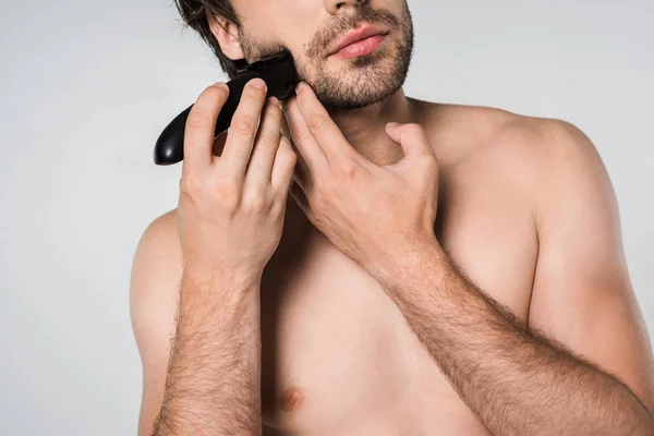 Vista parziale di uomo senza maglietta con taglierina elettrica barba da barba isolato su grigio — Foto stock