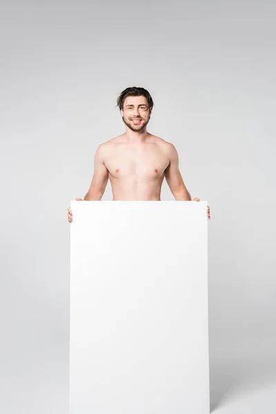 Sonriente hombre sin camisa con pancarta en blanco sobre fondo gris - foto de stock