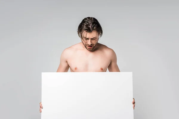 Ritratto di bell'uomo a petto nudo che guarda striscione bianco in mani isolate su grigio — Foto stock