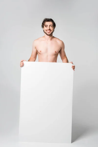 Hombre guapo sonriente con pancarta en blanco sobre fondo gris - foto de stock