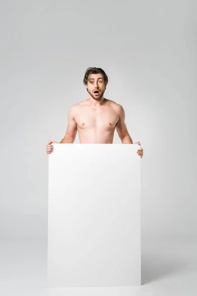 Shocked man with blank banner looking at camera on grey background — Stock Photo