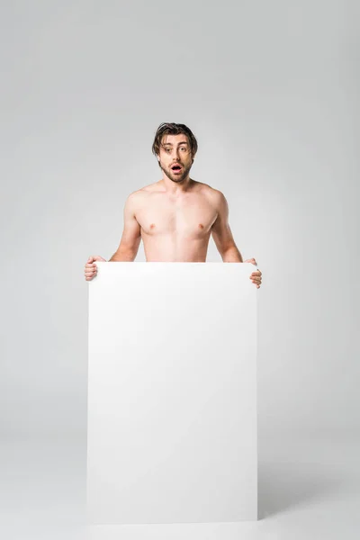 Homme choqué avec bannière vierge regardant la caméra sur fond gris — Photo de stock