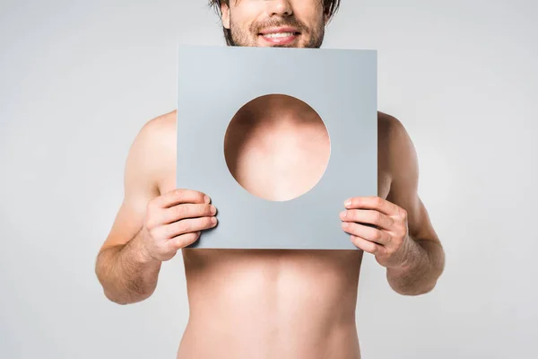 Plan recadré d'un homme souriant tenant un cercle de papier isolé sur du gris — Photo de stock