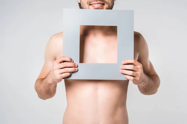 Cropped shot of smiling man holding paper square figure isolated on grey — Stock Photo