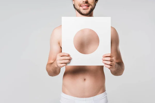 Cropped shot of smiling man in underwear holding white paper circle figure isolated on grey — Stock Photo