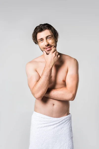 Портрет красивого мужчины в белом полотенце, смотрящего на камеру, изолированную на сером — стоковое фото