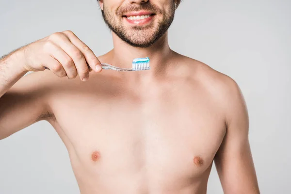 Vista parcial del hombre sonriente con cepillo de dientes aislado en gris - foto de stock