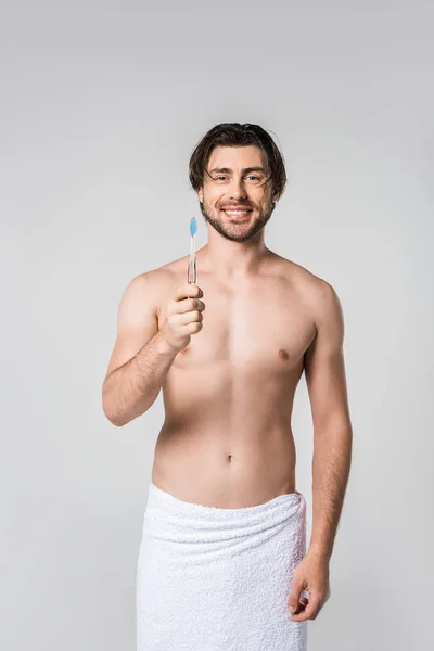 Portrait of cheerful man in white towel with tooth brush isolated on grey — Stock Photo