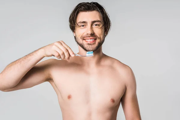 Retrato de homem sem camisa sorridente com escova de dentes isolada em cinza — Fotografia de Stock