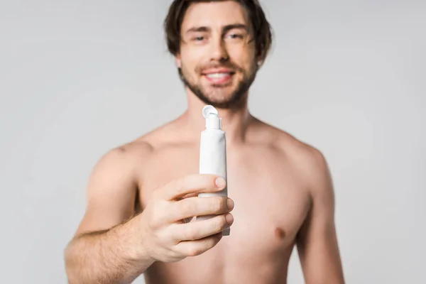 Selective focus of cheerful shirtless man showing toothpaste isolated on grey — Stock Photo