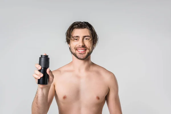 Portrait of smiling shirtless man with male deodorant isolated on grey — Stock Photo