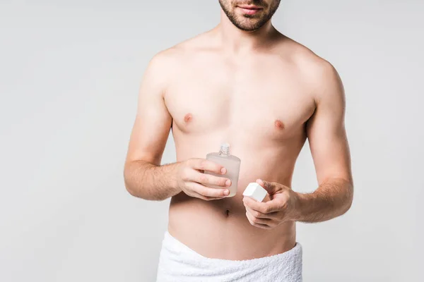 Tiro recortado de hombre en toalla blanca con perfume masculino aislado en gris - foto de stock