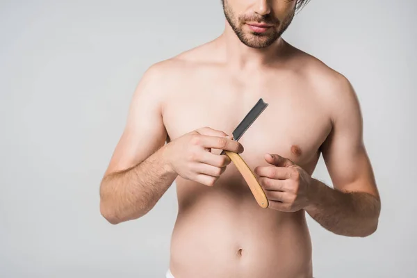 Partial view of shirtless man with straight razor in hands isolated on grey — Stock Photo