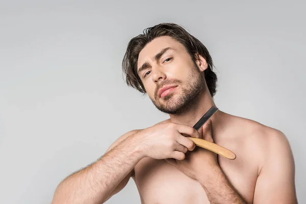 Retrato de hombre sin camisa con navaja de afeitar en las manos aisladas en gris - foto de stock