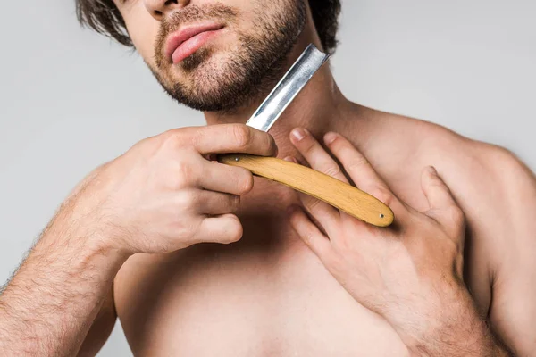 Cropped shot of man with straight razor in hands shaving beard isolated on grey — Stock Photo