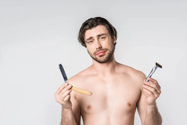 Portrait d'un homme torse nu avec des rasoirs dans les mains regardant la caméra isolée sur gris — Photo de stock