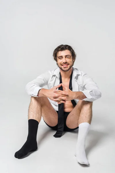 Hombre sonriente en camisa, ropa interior y calcetines blancos y negros sobre fondo gris - foto de stock