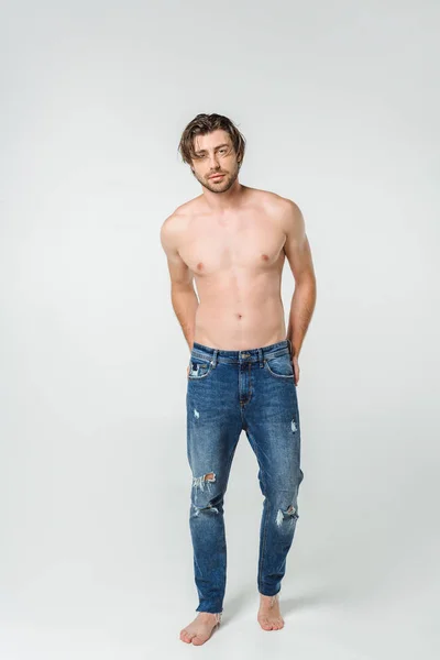 Young shirtless man in jeans posing on grey backdrop — Stock Photo